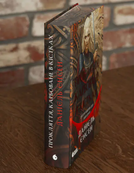 Корінець та обкладинка книги Прокляття, карбоване в кістках Даніель Єнсен