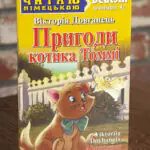 Пригоди котика Томмі Німецька мова — передня обкладинка на дерев’яній поверхні
