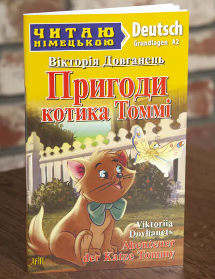 Пригоди котика Томмі Німецька мова — передня обкладинка на дерев’яній поверхні