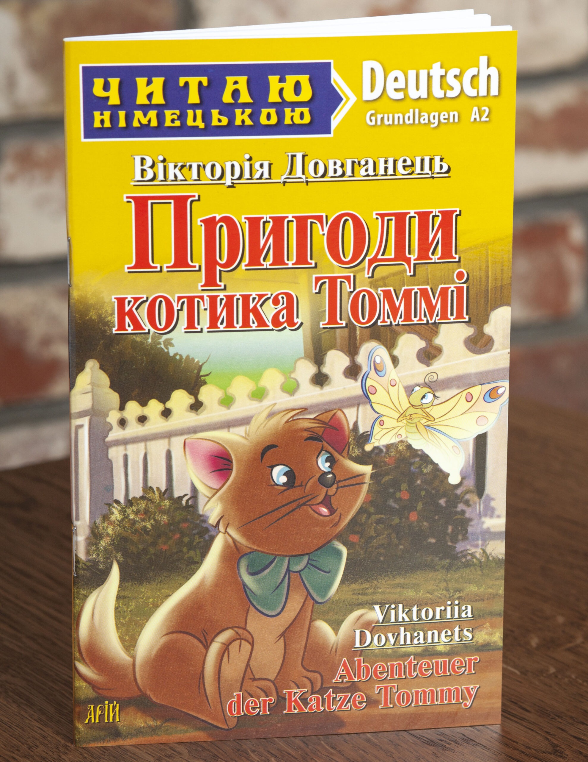 Пригоди котика Томмі Німецька мова — передня обкладинка на дерев’яній поверхні Пригоди котика Томмі Німецька мова — передня обкладинка на дерев’яній поверхні